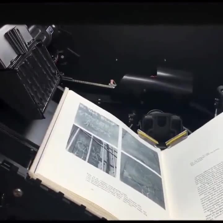 Libro patrimonial con una lámina a color, abierto sobre la cuna de un escáner de libros